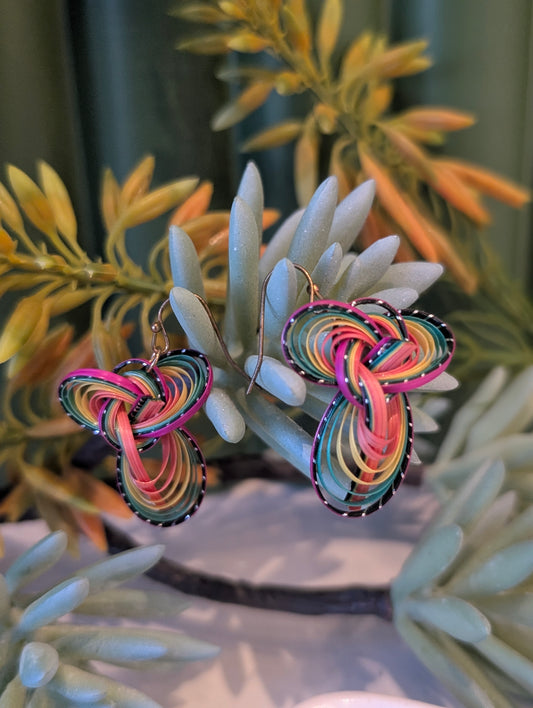 Colorful knotted earrings on a plant background